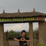 student doing the UO sign in front of Awash Falls Lodge